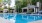 a swimming pool with chairs and umbrellas by a building